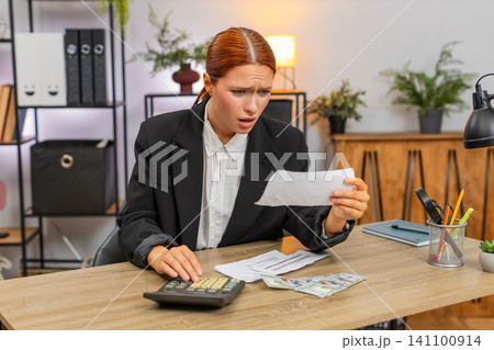 Young businesswoman checks bills with calculator sees negative balance worries about future expenses 141100914