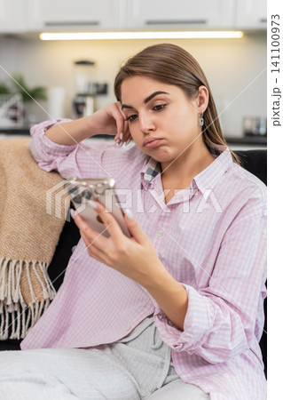 Young woman tired of news feed puts smartphone down closes eyes breathes seeking break from gadgets Young woman tired of news feed puts smartphone down closes eyes breathes seeking break from gadgets 141100973