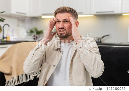 Young man suffers strong headache massages temples closes eyes slow breath seeks comfort calm relief 141100983