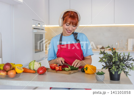 Young woman slices cucumber tomato on cutting board makes colorful salad and tastes fresh bite smile Young woman slices cucumber tomato on cutting board makes colorful salad and tastes fresh bite smile 141101058
