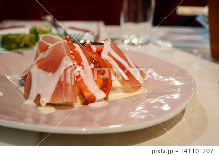 生ハムとトマトを盛り付けた前菜料理 生ハムとトマトを盛り付けた前菜料理 141101207