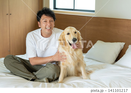 ベッドの上でゴールデンレトリバーとふれあう男性 ベッドの上でゴールデンレトリバーとふれあう男性 141101217
