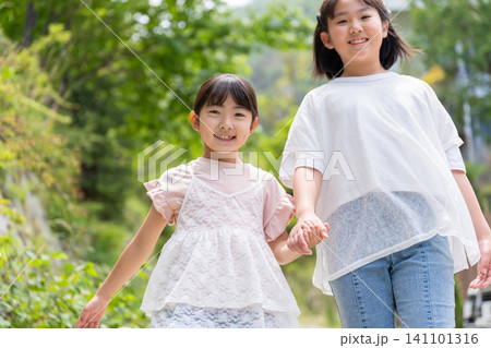 手をつないで歩く笑顔の女の子二人 手をつないで歩く笑顔の女の子二人 141101316