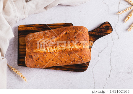 Fresh baked ciabatta loaf bread on a cutting board on the table top view 141102163