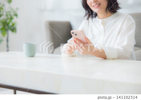 リビングでスマホを見る若い女性 リビングでスマホを見る若い女性 141102314