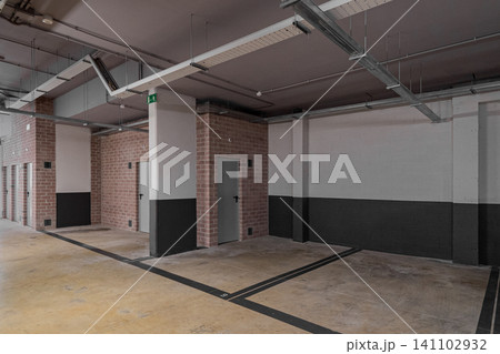 Empty modern parking garage with concrete floors and brick walls. Industrial design with minimalistic features and no vehicles present. Empty modern parking garage with concrete floors and brick walls. Industrial design with minimalistic features and no vehicles present. 141102932