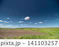 Wide rural field under blue sky with scattered clouds Wide rural field under blue sky with scattered clouds 141103257