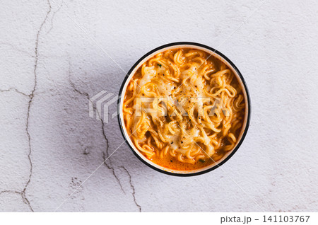 Close up of hot Korean ramen with melted cheese in a bowl on the table top view Close up of hot Korean ramen with melted cheese in a bowl on the table top view 141103767