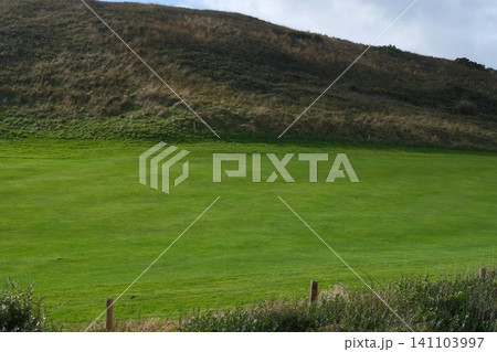 Green grass smooth even golf course field among the hills in France. Professional sport and hobby, entrtainment during traveling or vacations. Grassy surface maintenance Green grass smooth even golf course field among the hills in France. Professional sport and hobby, entrtainment during traveling or vacations. Grassy surface maintenance 141103997