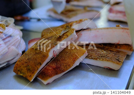 market pork lard. Stack of thick sliced cured pork belly with visible fat layers and rind texture arranged for sale as traditional spanish food product in local market setting market pork lard. Stack of thick sliced cured pork belly with visible fat layers and rind texture arranged for sale as traditional spanish food product in local market setting 141104049