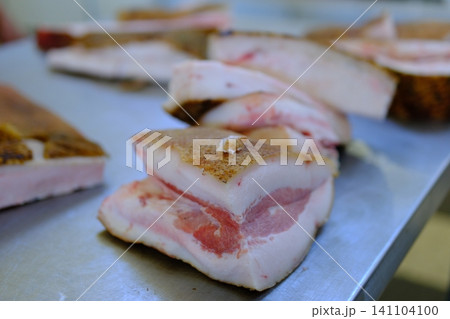 market pork lard. Stack of thick sliced cured pork belly with visible fat layers and rind texture arranged for sale as traditional spanish food product in local market setting market pork lard. Stack of thick sliced cured pork belly with visible fat layers and rind texture arranged for sale as traditional spanish food product in local market setting 141104100