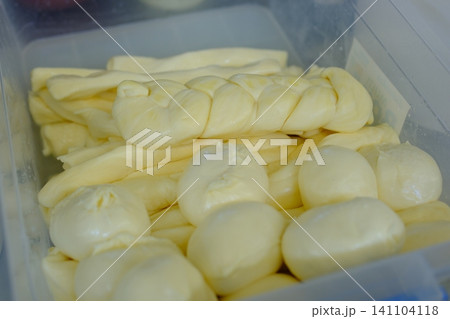 Fresh suluguni and braided mozzarella cheese in container at farmer market traditional handmade dairy products Fresh suluguni and braided mozzarella cheese in container at farmer market traditional handmade dairy products 141104118