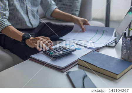 Male Entrepreneur or Remote Worker Calculating Budget and Analyzing Documents at Home Office Couch. 141104267