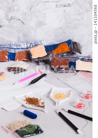 Small crystals in containers and bags for diamond mosaic on the table vertical view Small crystals in containers and bags for diamond mosaic on the table vertical view 141104568