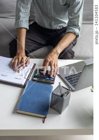 Man working on financial reports and business data analytics at home office. 141104583