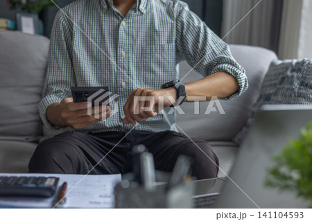 Close-up man's hand pairing, syncing, or checking a notification between his smartphone and his smartwatch. Close-up man's hand pairing, syncing, or checking a notification between his smartphone and his smartwatch. 141104593