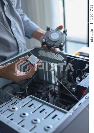 Computer engineer repair and assembling high-performance PC, CPU and cooler at workshop desk. Computer engineer repair and assembling high-performance PC, CPU and cooler at workshop desk. 141104715