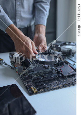 Close up of electronic technician hands working on computer hardware and mainboard repair. 141104894