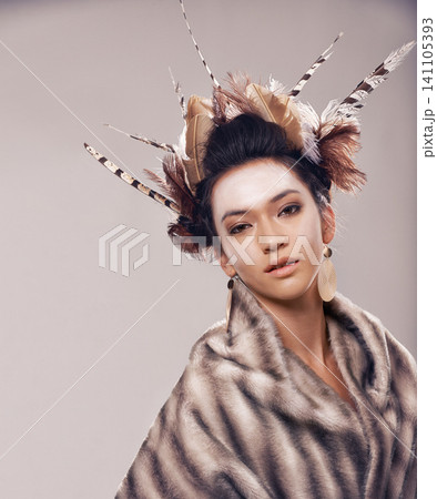 Woman, portrait and cultural fashion with Native American in tradition or art on a gray studio background. Female person with feather, face paint or stylish tribal clothing of goddess in beauty 141105393