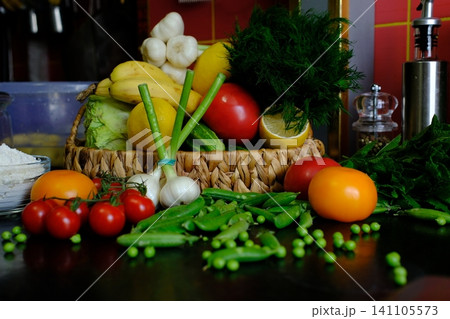 Fresh vegetables and fruit in woven basket with tomatoes peas cabbage peppers lemon and dill on black tablecloth close up Fresh vegetables and fruit in woven basket with tomatoes peas cabbage peppers lemon and dill on black tablecloth close up 141105573