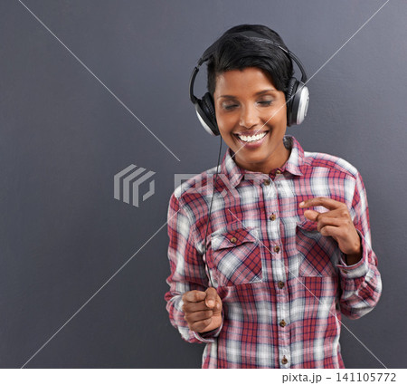 Happy woman, dancing and listening with headphones for music or podcast on a gray studio background. Young female person or Indian with smile, enjoying audio sound track with headset on mockup space 141105772