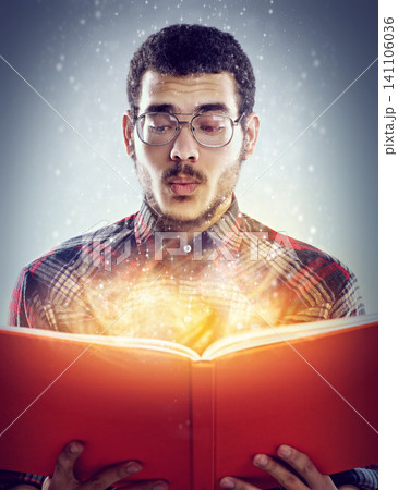 Thinking, glowing book and man with story, fantasy and education on grey studio background. Person, model and guy with novel and literature with knowledge and learning with light, creative or magic 141106036