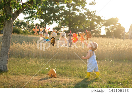 The baby reaches for the toys hanging on the rope in the garden at sunset The baby reaches for the toys hanging on the rope in the garden at sunset 141106158