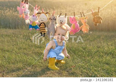 A funny laughing boy is depicted against the backdrop of a pile of stuffed animals hanging from a clothesline. A funny laughing boy is depicted against the backdrop of a pile of stuffed animals hanging from a clothesline. 141106181