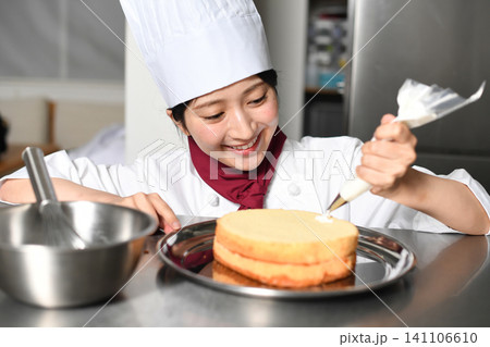 アジア人の女性パティシエがケーキを仕上げるイメージ アジア人の女性パティシエがケーキを仕上げるイメージ 141106610