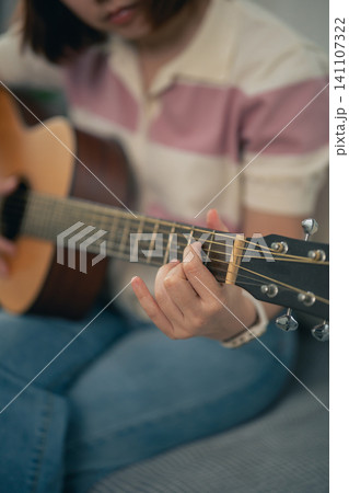 Person playing acoustic guitar close-up on strings and finger positioning Person playing acoustic guitar close-up on strings and finger positioning 141107322