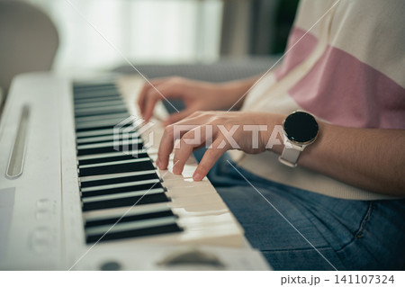 Close-up of person wearing smartwatch playing an electronic piano keyboard indoors Close-up of person wearing smartwatch playing an electronic piano keyboard indoors 141107324