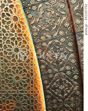 Relief texture of metal wall with carved geometric patterns. Relief texture of metal wall with carved geometric patterns. 141107702