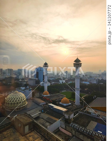 Urban landscape view with twin minarets against a sunset. Urban landscape view with twin minarets against a sunset. 141107772