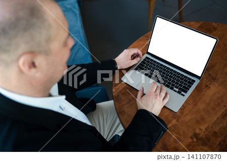 Businessman working on laptop at cafe table. Businessman working on laptop at cafe table. 141107870