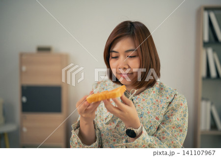 Young woman holding slice of bread indoors focusing on food detail 141107967