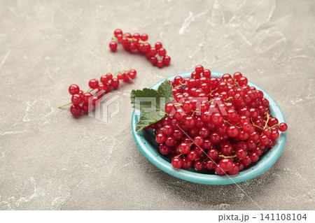 Red currants on blue plate on grey concrete background. Fresh and vibrant food photography for healthy eating. 141108104