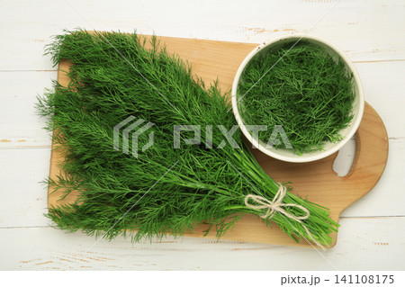 Bunch of green dill on cutting board on light background. Bunch of green dill on cutting board on light background. 141108175