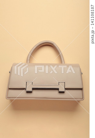 Beige female bag on beige background. Vertical photo Beige female bag on beige background. Vertical photo 141108187