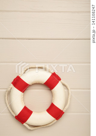 Summer beach background with mini lifebuoy on light wooden background. Top view Summer beach background with mini lifebuoy on light wooden background. Top view 141108247