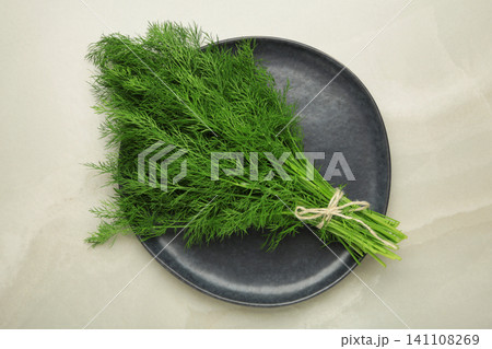 Bunch of green dill on dark plate on grey background. Bunch of green dill on dark plate on grey background. 141108269