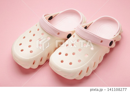 Mykolaiv, Ukraine - April 25, 2026: Couple of white Crocs sandals on pink background. 141108277