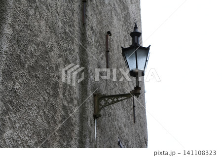 Close-Up View of a Historic Vintage Street Lantern Mounted on a Rough Textured Plaster Wall 141108323