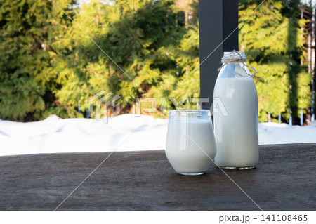 Glass of milk and bottle on outdoor table Glass of milk and bottle on outdoor table 141108465