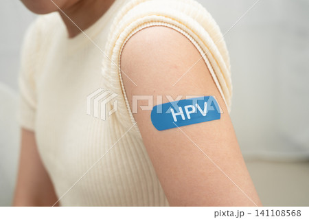 HPV, Human papillomavirus, Asian young woman receiving vaccine with blue bandage. HPV, Human papillomavirus, Asian young woman receiving vaccine with blue bandage. 141108568