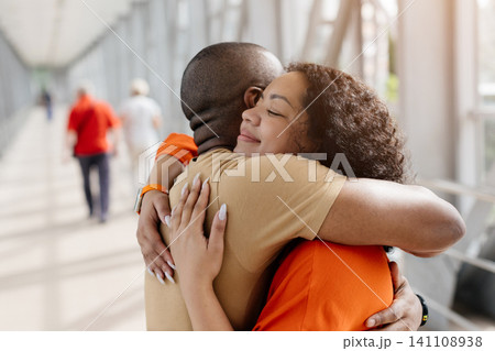 Close view of young Black couple hugging in airport, capturing emotional reunion 141108938