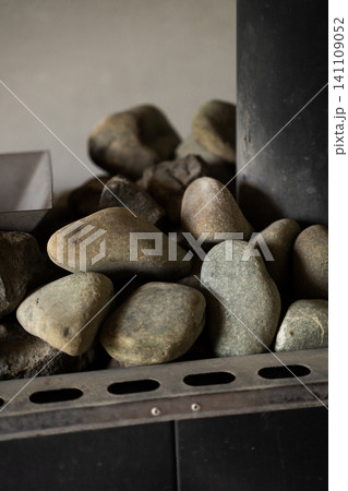 Sauna heater full of natural stones providing warmth and steam for relaxation and wellness indoors 141109052