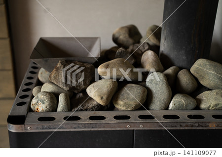 Sauna heater full of rocks generating heat and steam for relaxing wellness and traditional bath Sauna heater full of rocks generating heat and steam for relaxing wellness and traditional bath 141109077
