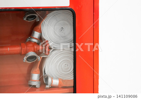 Fire hose station with rolled hoses and bright red emergency equipment inside a protective cabinet Fire hose station with rolled hoses and bright red emergency equipment inside a protective cabinet 141109086