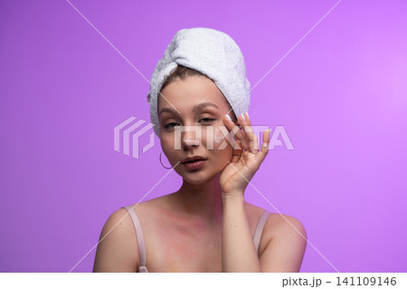 Young woman gently applying moisturizer to her face in a self-care routine, hydrating skin for a healthy, glowing complexion and relaxed, fresh look in a studio headshot Young woman gently applying moisturizer to her face in a self-care routine, hydrating skin for a healthy, glowing complexion and relaxed, fresh look in a studio headshot 141109146