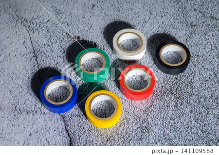 colorful rolls of electrical tape lie on a gray concrete surface forming a circle under bright light colorful rolls of electrical tape lie on a gray concrete surface forming a circle under bright light 141109588